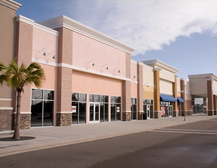Empty commercial building exterior with large windows and a parking lot.